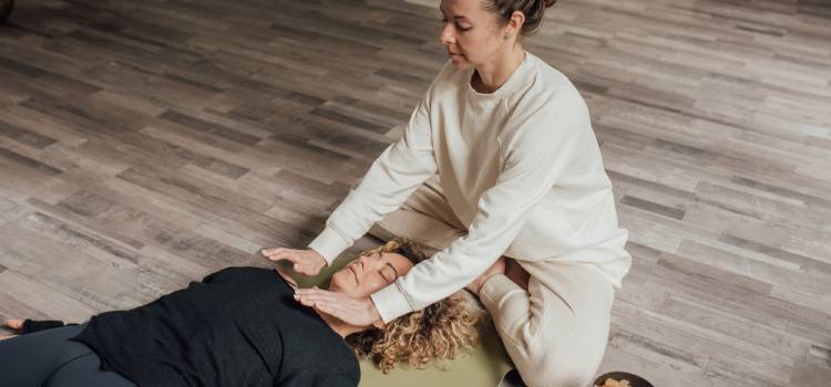 a female reiki master with both palms hovering over client laying on the floor